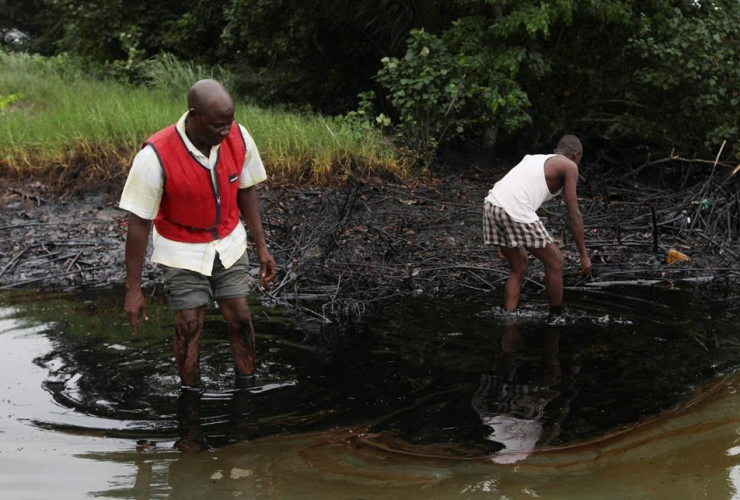 men walk in an oil slick covering a creek near Bodo City in the oil-rich Niger Delta region of Nigeria