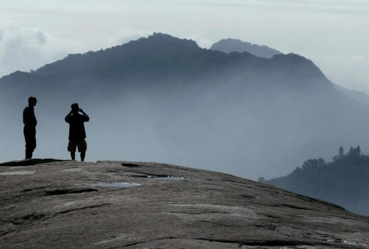 In this Oct. 3, 2016, file photo, Kyle Palmer, left, of Idaho waits as his son Lance Palmer of San Francisco, takes a photograph of the scene looking south from Beetle Rock at Giant Forest in Sequoia National Park, Calif.