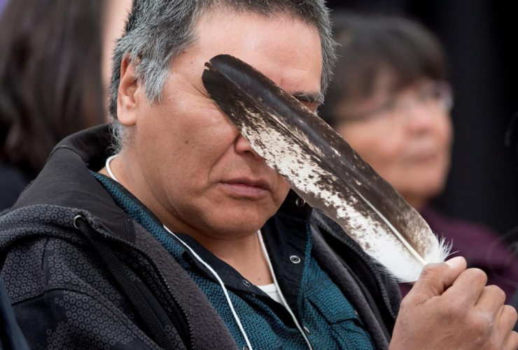 Terry Ladue holds a eagle feather to his face after speaking of his mother Jane Dick Ladue's murder at the National Inquiry into Missing and Murdered Indigenous Women and Girls taking place in Whitehorse on June 1, 2017.