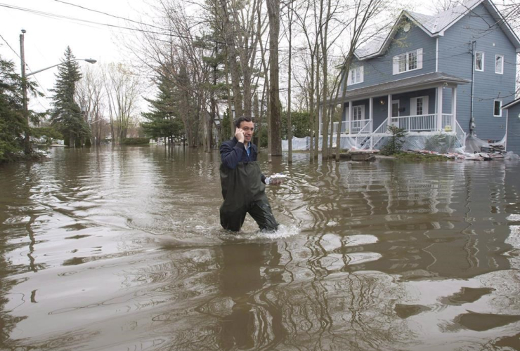 A man makes his way through the flooded streets in Laval, Que., on Wednesday, May 10, 2017.