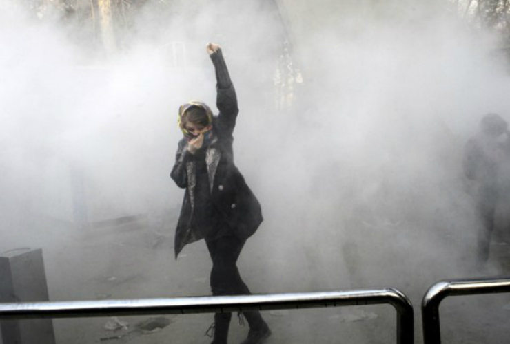 An Iranian protester raises her fist above her head.