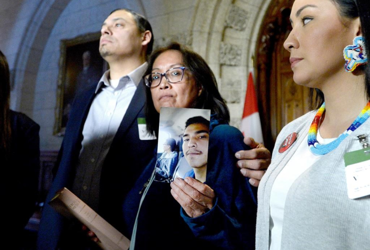 Debbie Baptiste holds up a photo of her son Colten Boushie, as the family spoke to reporters in the Foyer of the House of Commons after a day of meetings on Parliament Hill, in Ottawa on Tuesday, Feb. 13, 2018. THE CANADIAN PRESS/Justin Tang