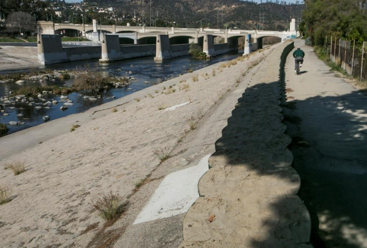 cyclist rides, flood control walls, Los Angeles, 