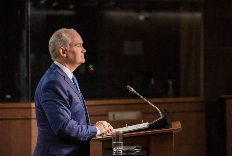 The right profile of a man standing before a podium, looking forward