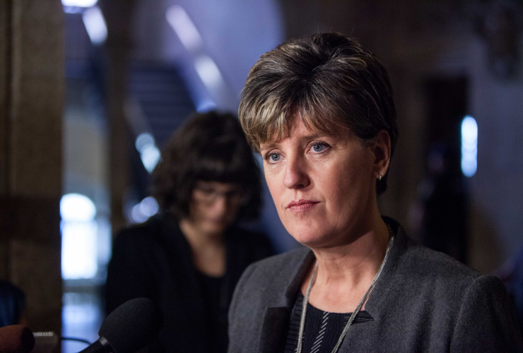 a woman with a short haircut and blue eyes looks past the camera