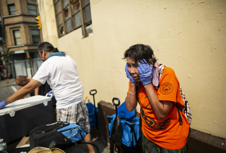 A person suffers in Vancouver's extreme heat, a blue cooler is visible in the background.