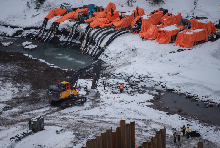 aerial view of a construction site on the Clore river. large pumps divert the water and heavy mahcinery and workers are working in the area