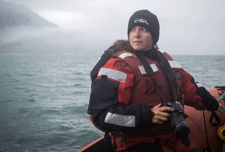 a woman on a boat wearing a jacket and a life jacket holding a camera