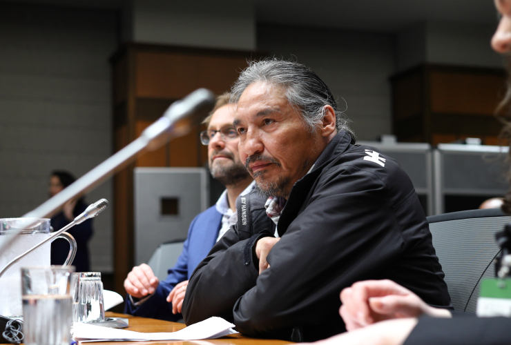 ACFN Chief Allan Adam sits at a table in the House of Commons committee room, waiting for the meeting to start.