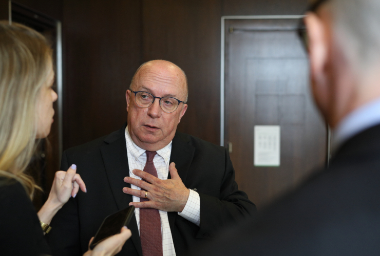 a bald man answers questions from a reporter