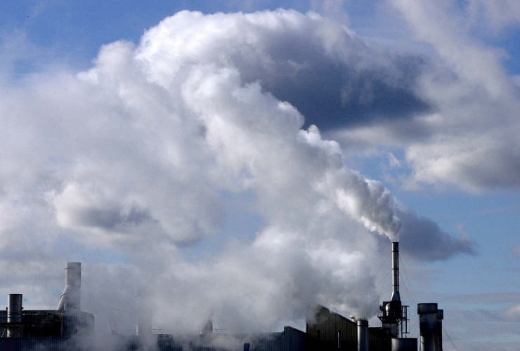 air pollution coming from smoke stacks against a blue sky