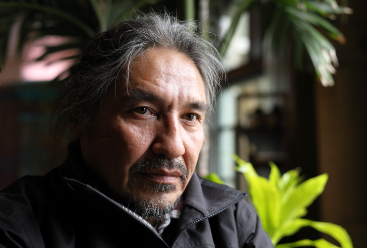 Chief Allan Adam sits looking out the window with some hotel greenery in the background