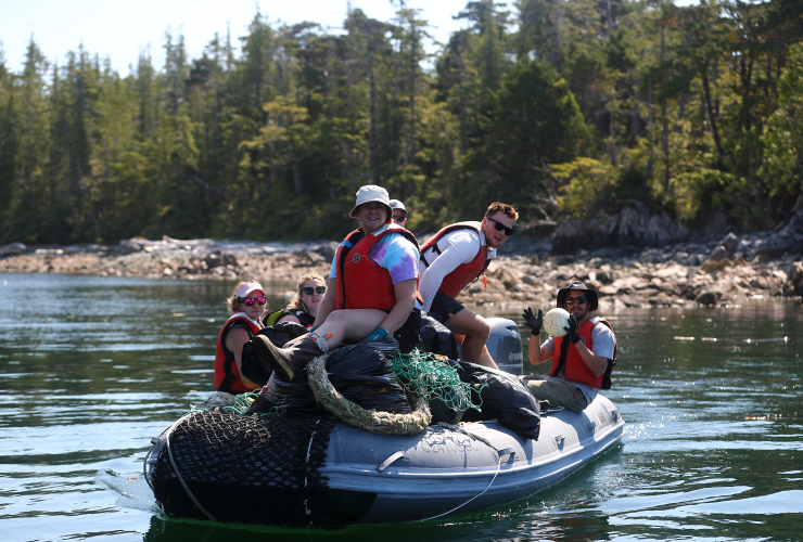 six people sit on a zodiac full of garbage