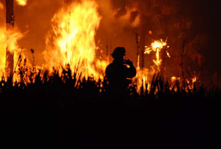 silhouette of a firefighter in front of a wildfire