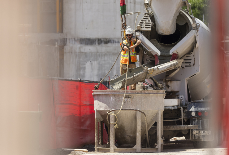 A worker pours concrete into a crane bucket