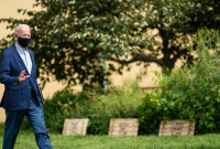 A man in a mask walks across a lawn