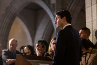 a man in a suit stands at a podium, looking out at a crowd of people