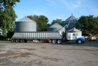 A truck unloads grain into a grain dryer at a farm