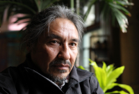 Chief Allan Adam sits looking out the window with some hotel greenery in the background