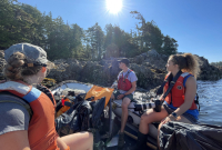 a group of people sit in a zodiac ona  nice sunny day