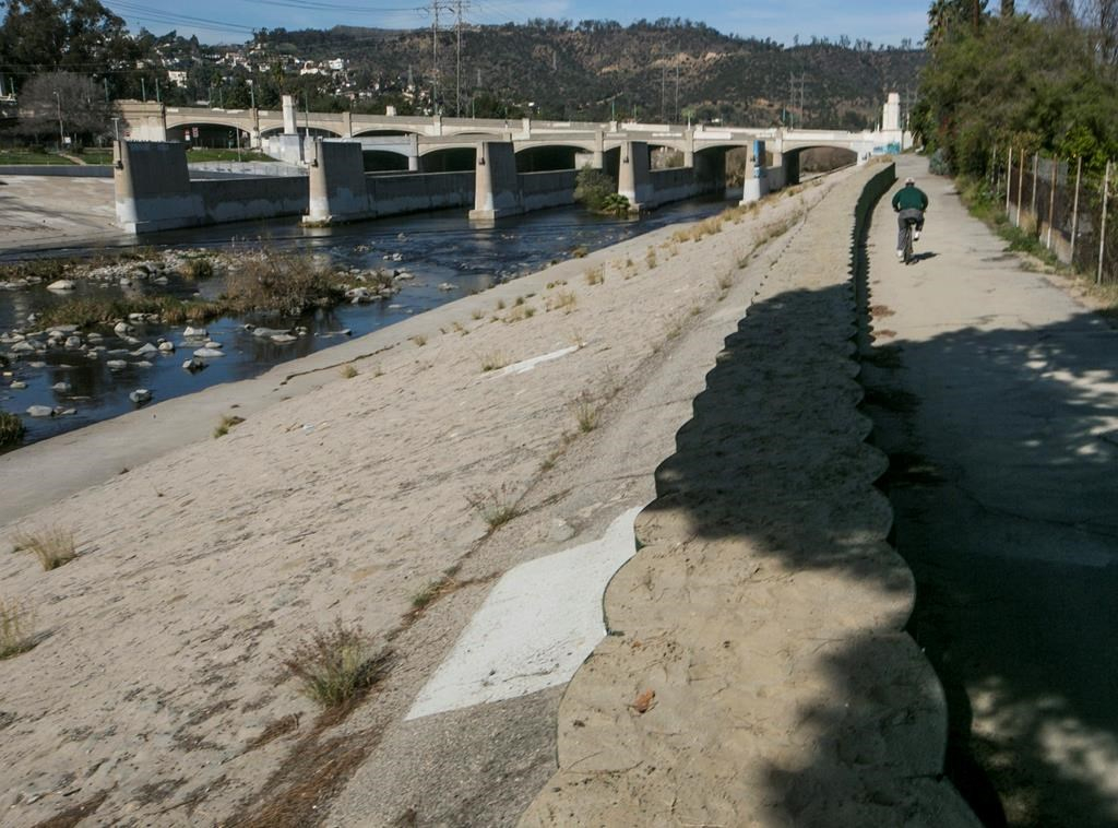 cyclist rides, flood control walls, Los Angeles, 