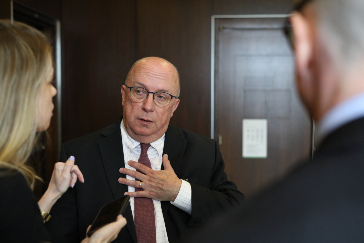 a bald man answers questions from a reporter