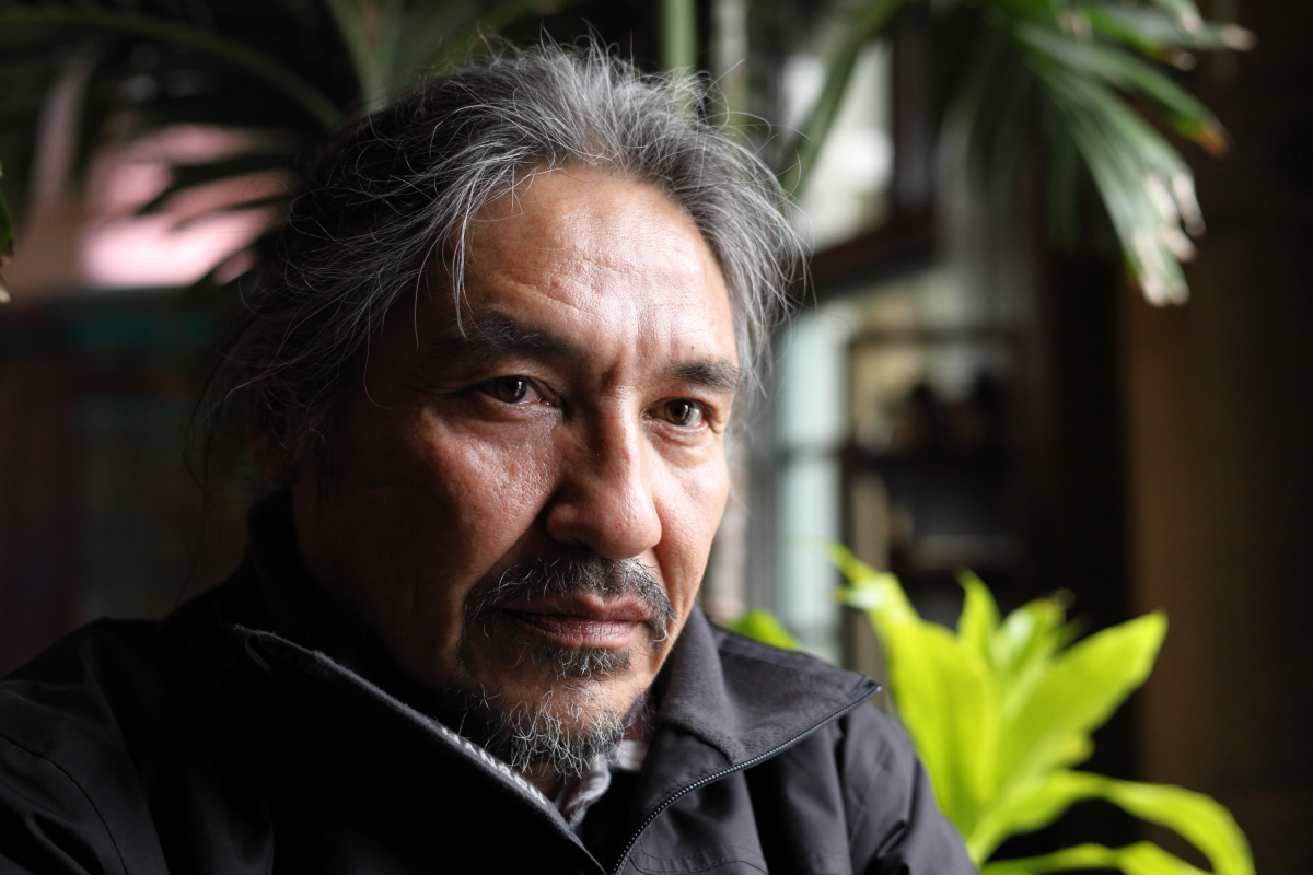 Chief Allan Adam sits looking out the window with some hotel greenery in the background