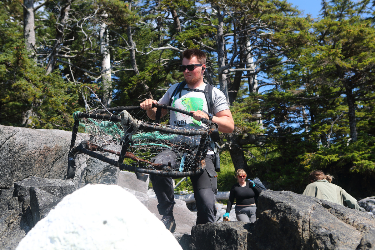 a crew member carries a crab trap to the zodiac