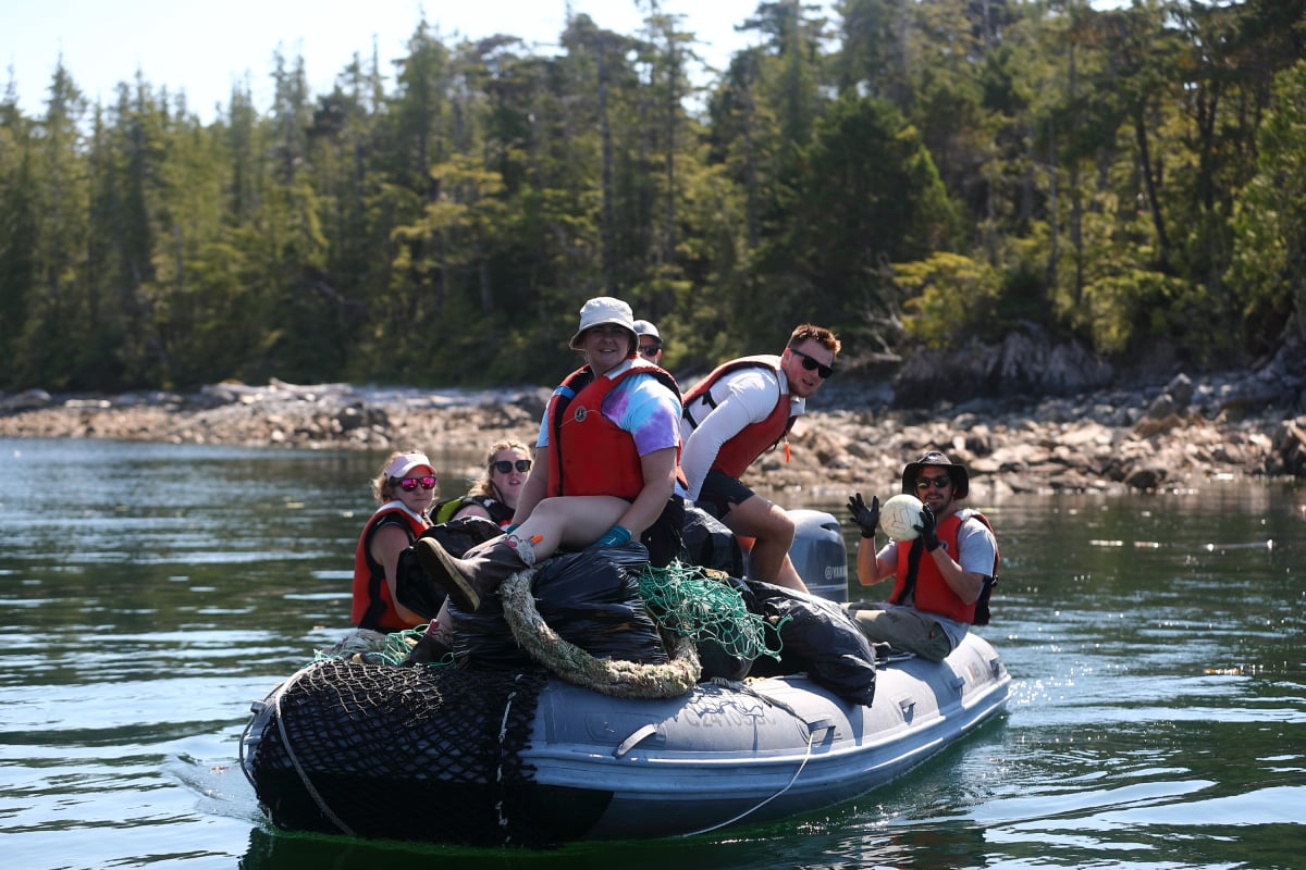 six people sit on a zodiac full of garbage