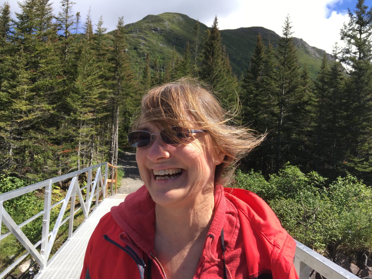 a woman in a red jacket smiles in the sun