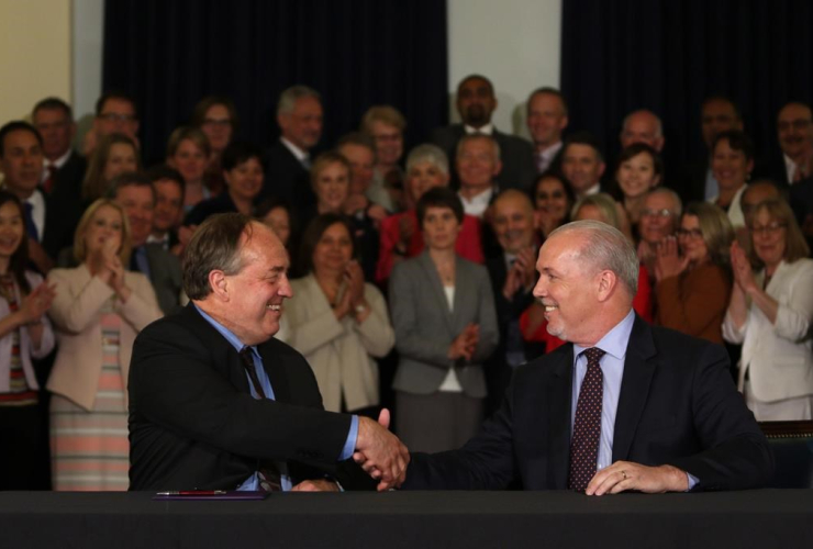 NDP leader John Horgan and Green party leader Andrew Weaver shake hands after signing an agreement on creating a stable minority government during a press conference in the Hall of Honour at Legislature in Victoria, B.C., on May 30, 2017.